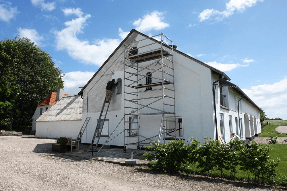 Man on scaffolds painting a house — Photo